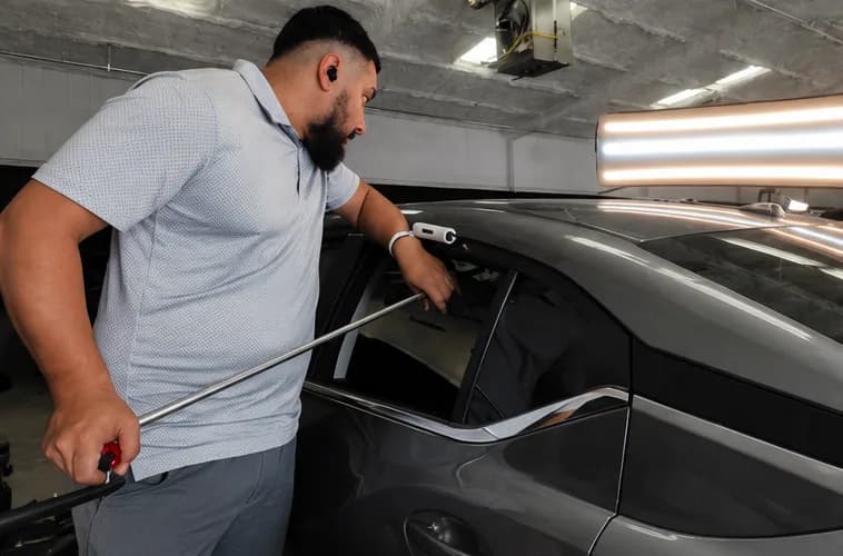 Xtreme Collision technician performing paintless dent repair on a hail-damaged vehicle